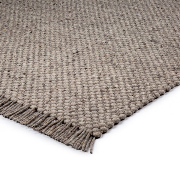 Een close-up van het Burano Dark Grey 618-613 vloerkleed (170x230 cm) met grof geweven structuur en franje langs één rand, tegen een witte achtergrond.