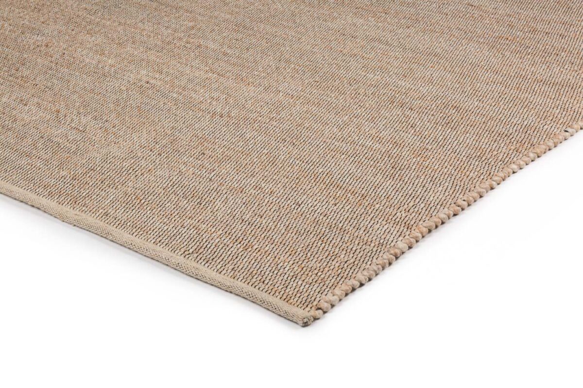 Een close-up van de hoek van het tapijt Bressano Beige 142 170x230 toont het eenvoudige, gestructureerde weefsel en de zacht afgeronde rand, allemaal in beige tegen een witte achtergrond.