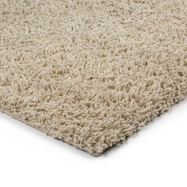 Close-up van de hoek van het Berbero Lungo Cloud White 815 200x300 tapijt, met dikke, beige shaggy vezels op een witte achtergrond.