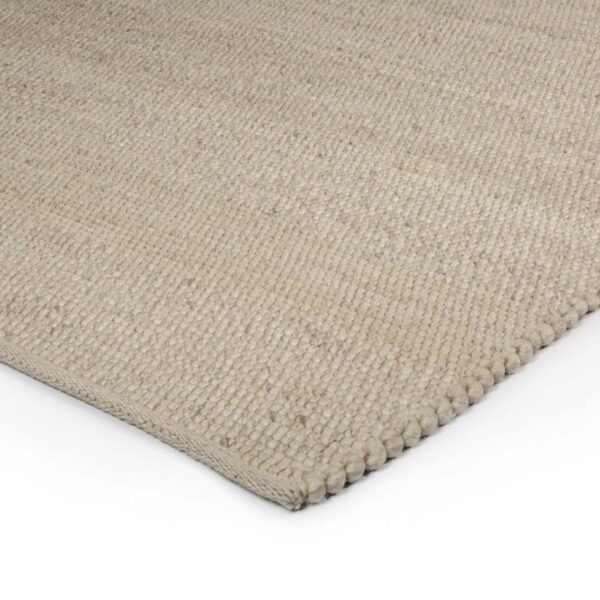 Een close-up van de hoek van het Verona ST Cloud White 815 170x230 tapijt toont de lichtbeige geweven textuur op een witte achtergrond.