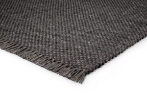 Een close-up van het Burano Anthracite 614-604 170x230 tapijt met donkergrijze structuur en franje, tegen een witte achtergrond.