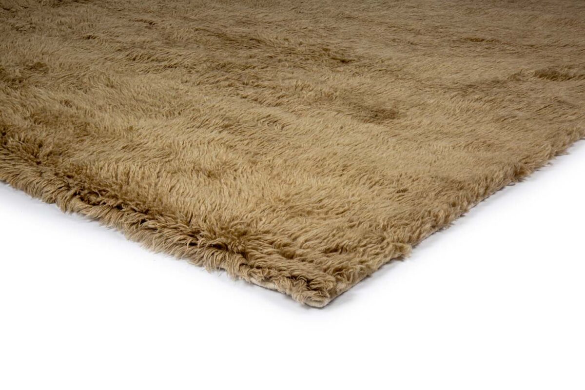 Een close-up van het Merano Beige 002 170x230 vloerkleed toont de zachte, dikke, ruige beige vezels tegen een witte achtergrond.