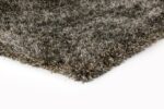 Een close-up van het New Paulo Grey mix 862 200x300 vloerkleed toont de dikke, ruige donkergrijze structuurvezels op een wit oppervlak.