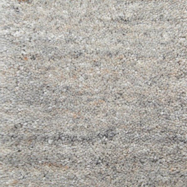 Close-up van New Berbero Grey 834 200x300 tapijt: lichtgrijs, gestructureerde lussenpool met subtiele kleurvariaties, met beige en donkergrijze vlekken. Het oppervlak ziet er zacht en dicht uit.