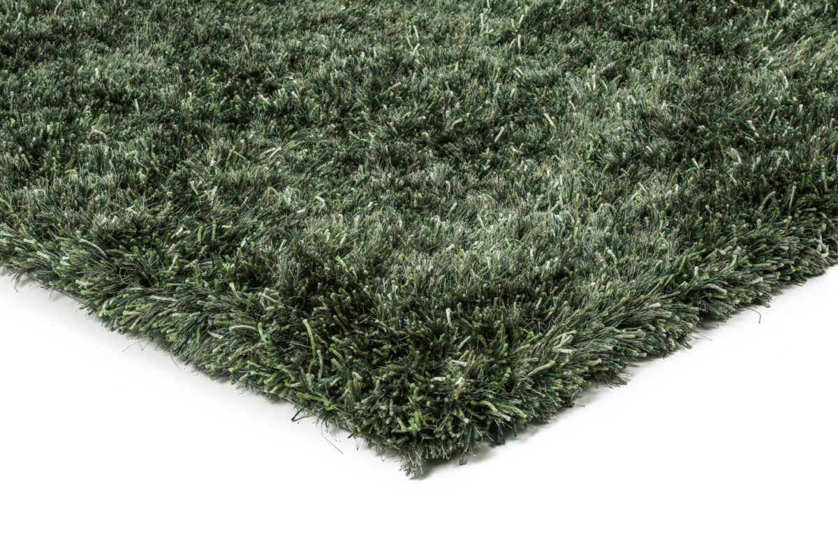 Een close-up van de hoek van het New Paulo Dark Green 442 170x230 vloerkleed toont de dikke shaggy vezels met textuur tegen een witte achtergrond.
