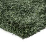 Een close-up van de hoek van het New Paulo Dark Green 442 170x230 vloerkleed toont de dikke shaggy vezels met textuur tegen een witte achtergrond.