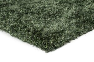 Een close-up van de hoek van het New Paulo Dark Green 442 170x230 vloerkleed toont de dikke shaggy vezels met textuur tegen een witte achtergrond.