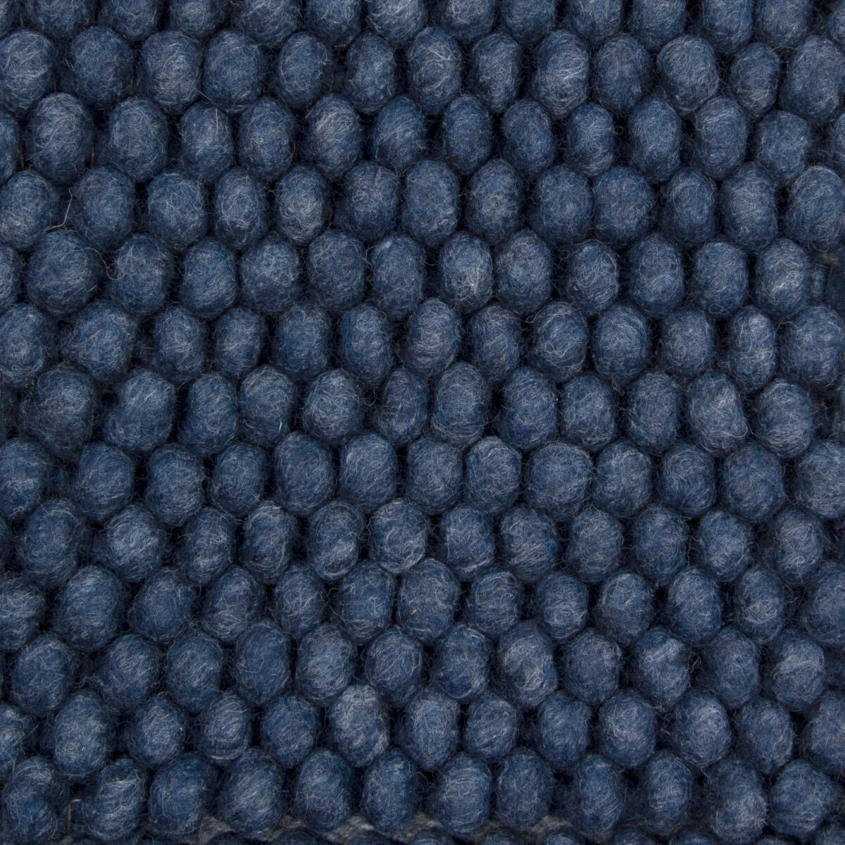 Close-up van het New Loop 290 Indigo 170x230 vloerkleed met een rasterpatroon van dicht op elkaar geplaatste, ronde blauwe bolletjes wol met een gestructureerd oppervlak.