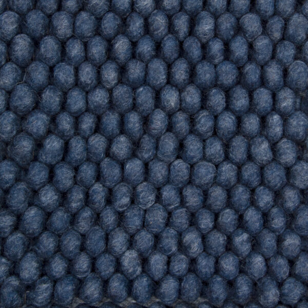 Close-up van het New Loop 290 Indigo 170x230 vloerkleed met een rasterpatroon van dicht op elkaar geplaatste, ronde blauwe bolletjes wol met een gestructureerd oppervlak.