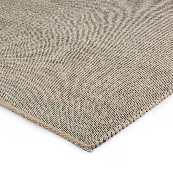 Een close-up van de hoek van het Bressano Light Beige 141 200x300 vloerkleed benadrukt het geweven oppervlak met textuur en de gedetailleerde stiksels aan de randen.