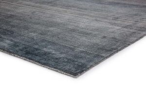 Een close-up van het Portofino Blue 01 170x230 vloerkleed onthult een zacht, gestructureerd oppervlak met een subtiel verloop en netjes afgewerkte randen, tegen een witte achtergrond.