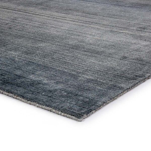 Een close-up van het Portofino Blue 01 170x230 vloerkleed onthult een zacht, gestructureerd oppervlak met een subtiel verloop en netjes afgewerkte randen, tegen een witte achtergrond.