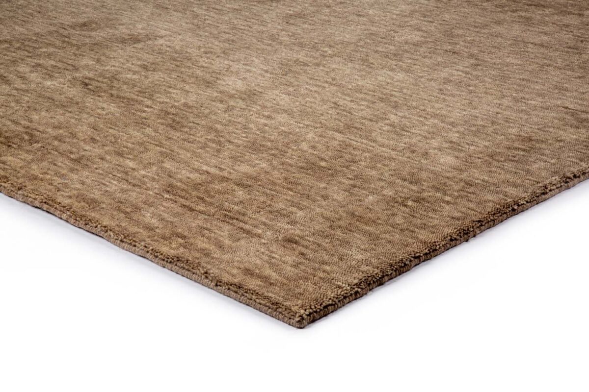 Een close-up van de hoek van het San Stefano Camel 09 200x300 rechthoekige, lichtbruine vloerkleed met structuur op een witte achtergrond.