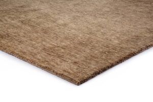 Een close-up van de hoek van het San Stefano Camel 09 200x300 rechthoekige, lichtbruine vloerkleed met structuur op een witte achtergrond.