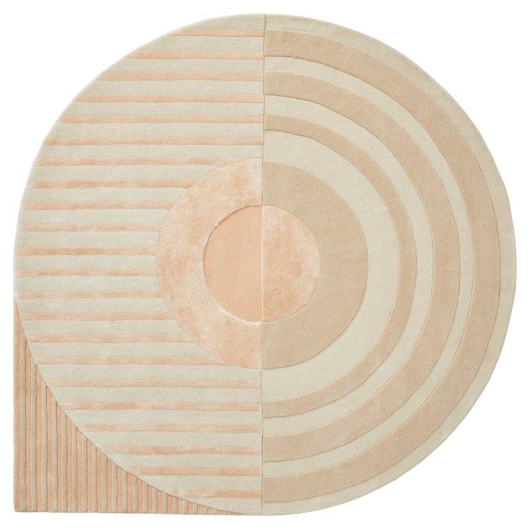 Het Fano Girare White Beige ø320 is een rond tapijt met een geometrisch patroon in beige tinten, met strepen aan de linkerkant, concentrische cirkels aan de rechterkant, een centrale effen cirkel en diagonale strepen in het kwart linksonder.