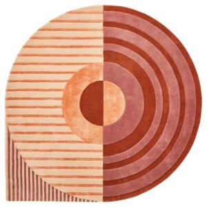 De Fano Girare Lychee ø320 is een rond tapijt met een modern geometrisch ontwerp: de ene helft heeft horizontale strepen in perzik en rood, terwijl de andere helft concentrische cirkels in rood en perzik toont, gecentreerd door een opvallende cirkel.
