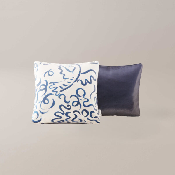 Twee vierkante Berard hoofdkussens: een met een witte hoes en blauwe abstracte lijnen, de andere in effen donkerblauw, beide tegen een lichte neutrale achtergrond.