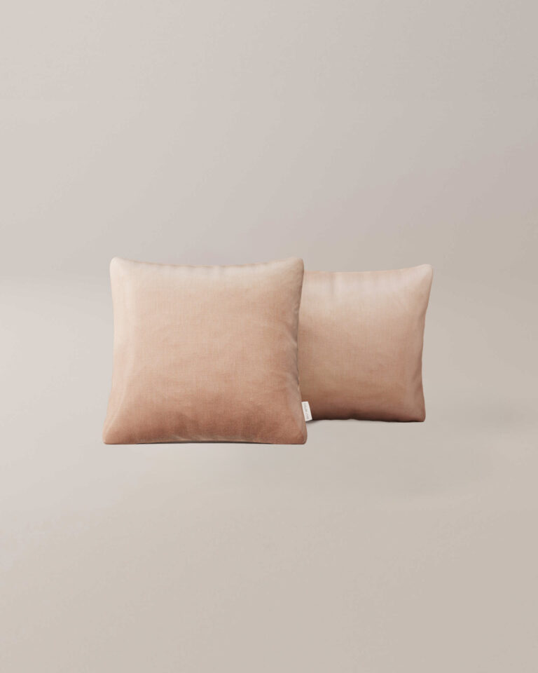 Twee Silver Rose beige vierkante kussens met een zachte, fluweelachtige textuur liggen naast elkaar tegen een effen, lichtgekleurde achtergrond.