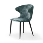 De Stoel Nick adore Azur / Aquamarine is een stijlvolle stoel van groen fluweel met een gebogen rugleuning, verticale stiksels en vier slanke zwarte metalen poten, afgebeeld op een witte achtergrond.