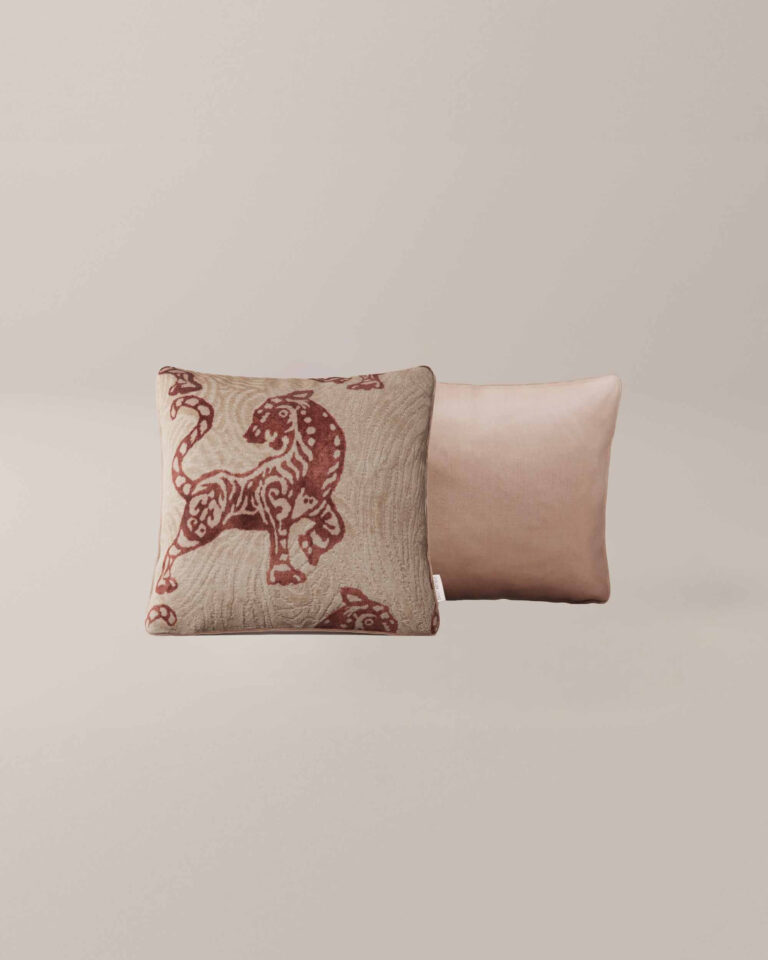 De Kaida Sierra set bestaat uit twee vierkante kussens: een met een rode, gestileerde tijger op beige en de andere in effen lichtroze, beide tegen een neutrale achtergrond.