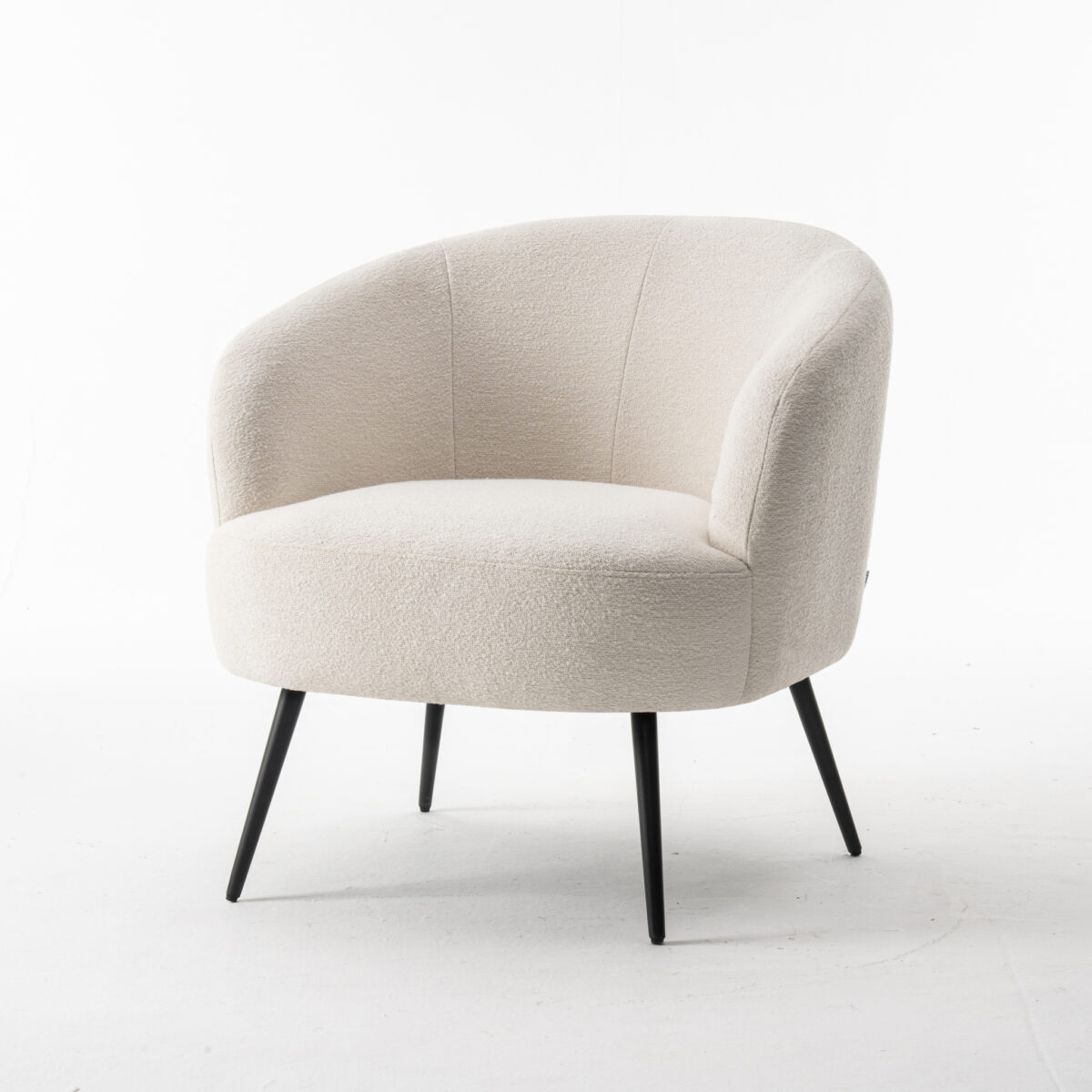 De Laura fauteuil Stof Teddy Ivory 101 is een moderne fauteuil met een gebogen rugleuning, bekleed met ivoorkleurige Teddy-stof en voorzien van vier slanke, schuine zwarte poten tegen een effen witte achtergrond.