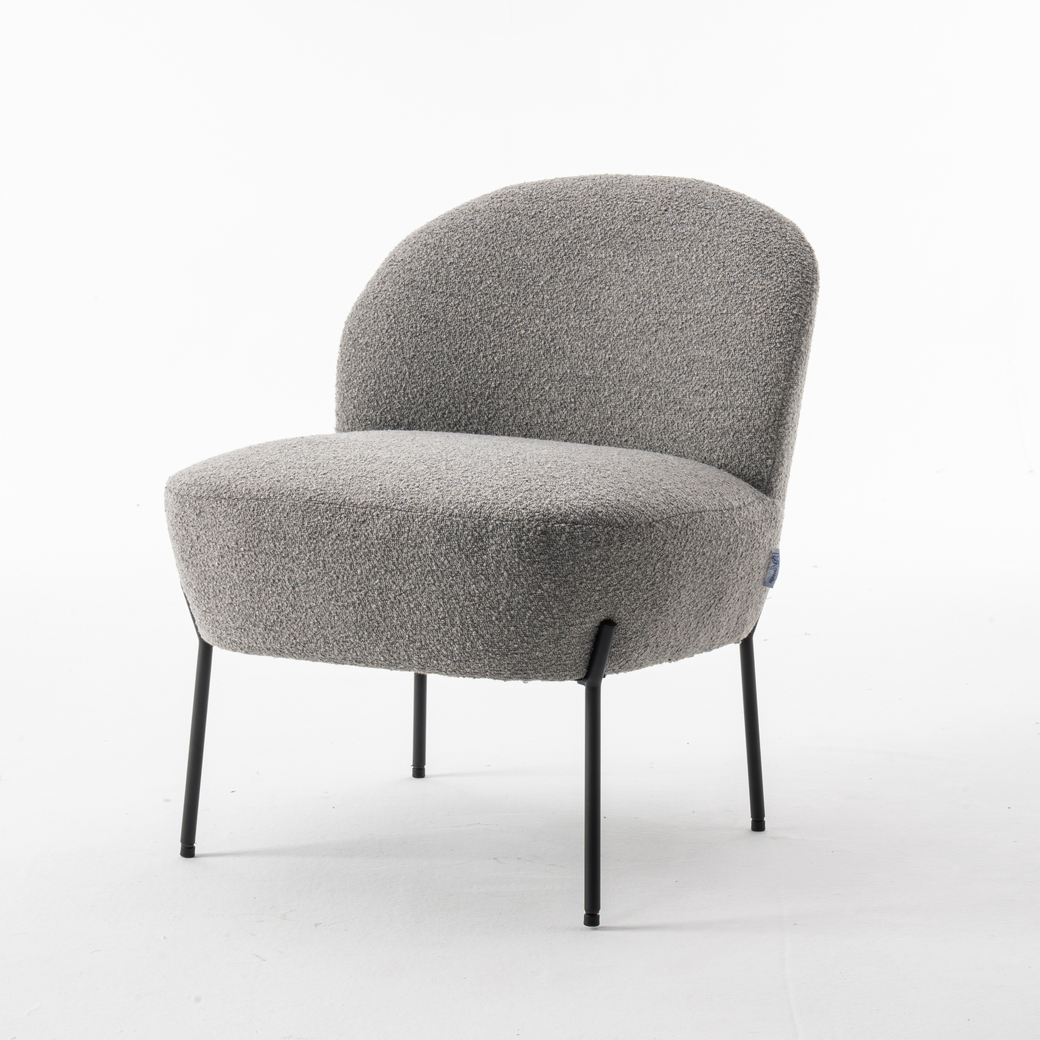 De Baudin fauteuil Stof Teddy Steel 149 is een moderne accentstoel met een afgeronde rugleuning en zitting van gestructureerde grijze stof op vier slanke zwarte metalen poten, afgebeeld tegen een effen witte achtergrond.