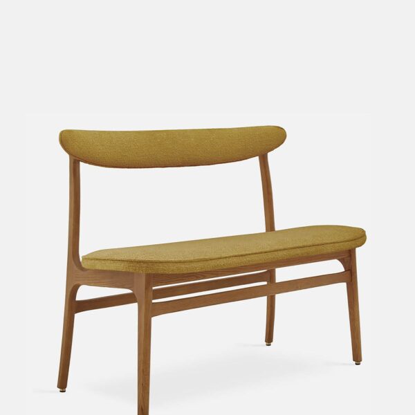 De 200-190 Bank Boucle Mustard Dark Wood heeft een mid-century modern ontwerp met een gebogen mosterdgele gestoffeerde zitting en rugleuning, slanke donkerhouten poten en een minimalistische stijl, tegen een effen witte achtergrond.
