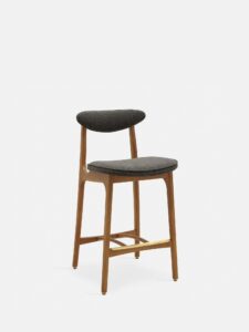 De 200-190 Barkruk S/65 heeft natuurlijk hout, een minimalistisch ontwerp en een gebogen gecapitonneerde zitting en rugleuning in wolgrijs-zwart tegen een effen witte achtergrond.