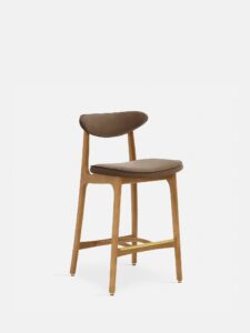 De 200-190 Barkruk S/65 is gemaakt van natuurlijk hout met een gebogen rugleuning en een met taupe fluweel beklede zitting, met moderne lijnen en schuine poten tegen een effen witte achtergrond.
