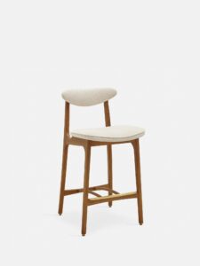 De 200-190 Barkruk S/65 heeft een modern minimalistisch ontwerp met een gebogen, lage rugleuning en een beklede zitting in marmerwitte stof. Slanke, schuine donkerhouten poten maken de look af tegen een effen witte achtergrond.