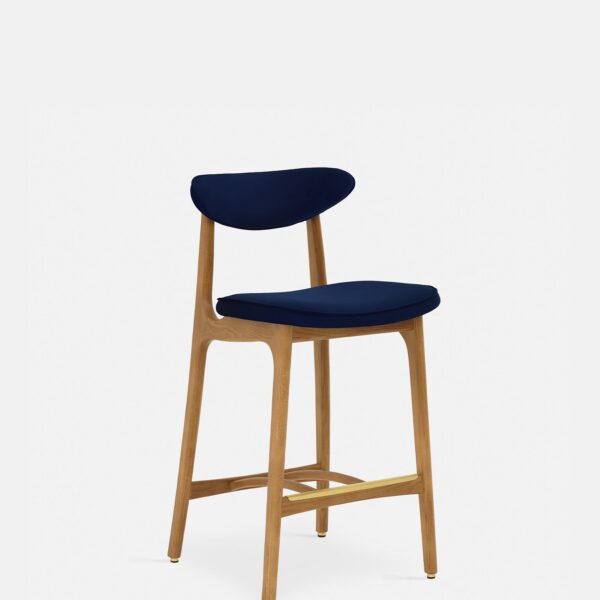 De 200-190 Barkruk S/65 heeft een modern frame van natuurlijk hout met een gebogen rugleuning en een met indigo fluweel beklede zitting en rugleuning, tegen een effen witte achtergrond.