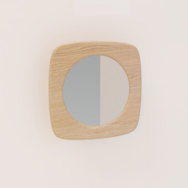 De SENTO SPIEGEL90 E02M, een ronde spiegel met een licht houten vierkant frame, is gemonteerd op een effen, lichtgekleurde muur en weerspiegelt een subtiele verticale verdeling van licht en schaduw.