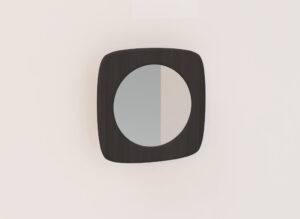 De SENTO SPIEGEL90 EL55, een ronde spiegel met een donkere vierkante houten lijst, hangt op een lichtbeige muur. De reflectie is verdeeld in lichte en donkere tinten, wat een subtiel geometrisch effect toevoegt.