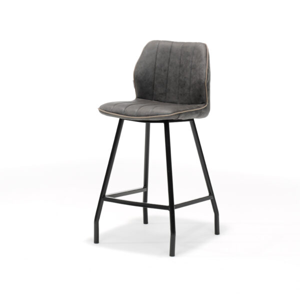 De Barkruk Gino zwart stof Soft Antraciet is een moderne barkruk met een gestoffeerde grijze zitting en rugleuning, verticale stiksels, slanke zwarte metalen poten met voetsteun, afgebeeld tegen een witte achtergrond.