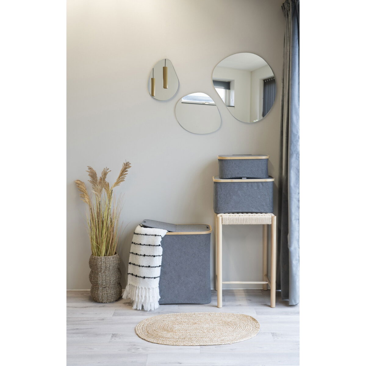 Minimalistisch interieur met twee manden, een gevlochten vaas met gedroogd gras, een gestreept kleed, een klein rond vloerkleed, een vloergordijn rechts en de Palermo Spiegelset - drie frameloze ronde wandspiegels. Licht en neutraal kleurenschema.