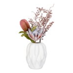 Een beige vaas van keramiek (19,5x19,5x26 cm) bevat kunstroze protea bloemen, roze bessen en groene bladeren, gerangschikt tegen een witte achtergrond.
