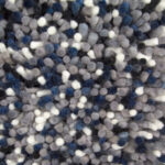 Close-up van het Alto Indigo 250 170x230 tapijt, met een dicht, gestructureerd oppervlak met zachte, ronde vezels in grijs-, blauw-, zwart- en wittinten.
