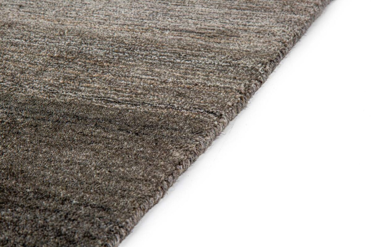 Close-up van de rand van het Portofino Beige 02 200x300 vloerkleed met een grijs en bruin structuurpatroon op een witte achtergrond.