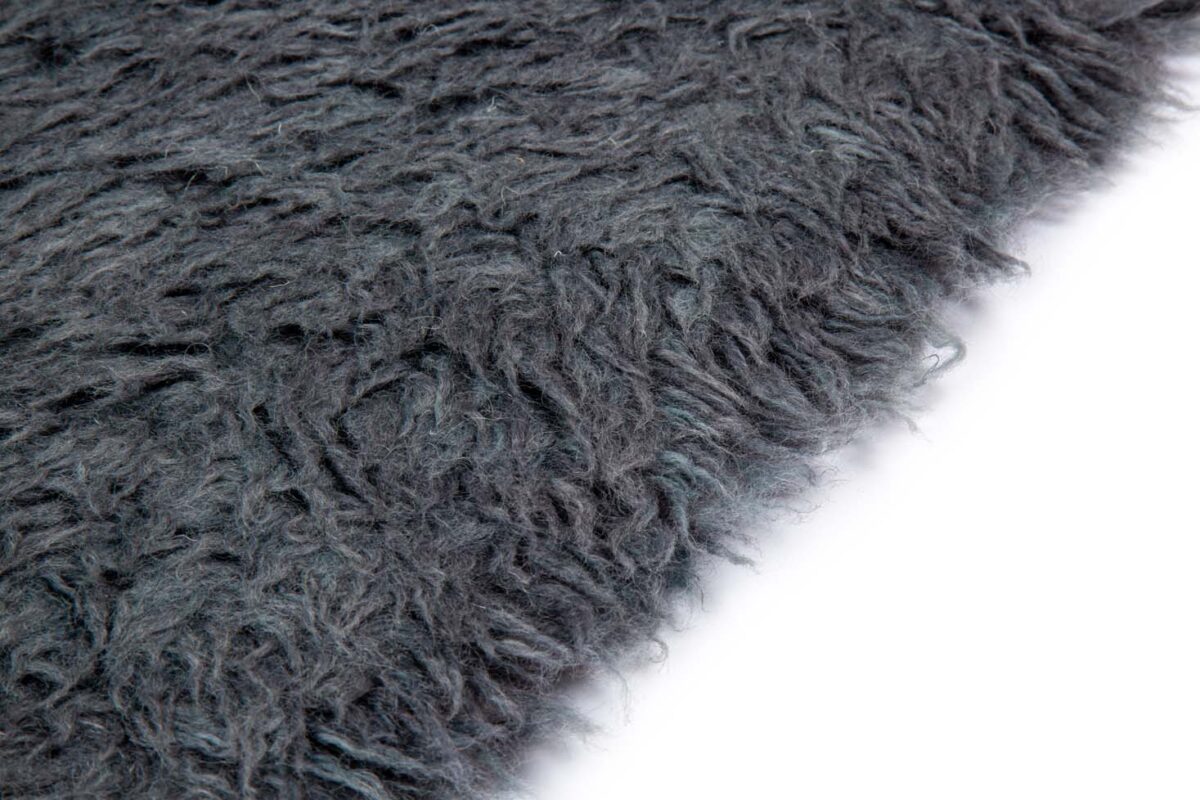 Close-up van het Merano Charcoal 013 200x300 tapijt met donkergrijze kleur, ruige textuur en lange vezels tegen een witte achtergrond.
