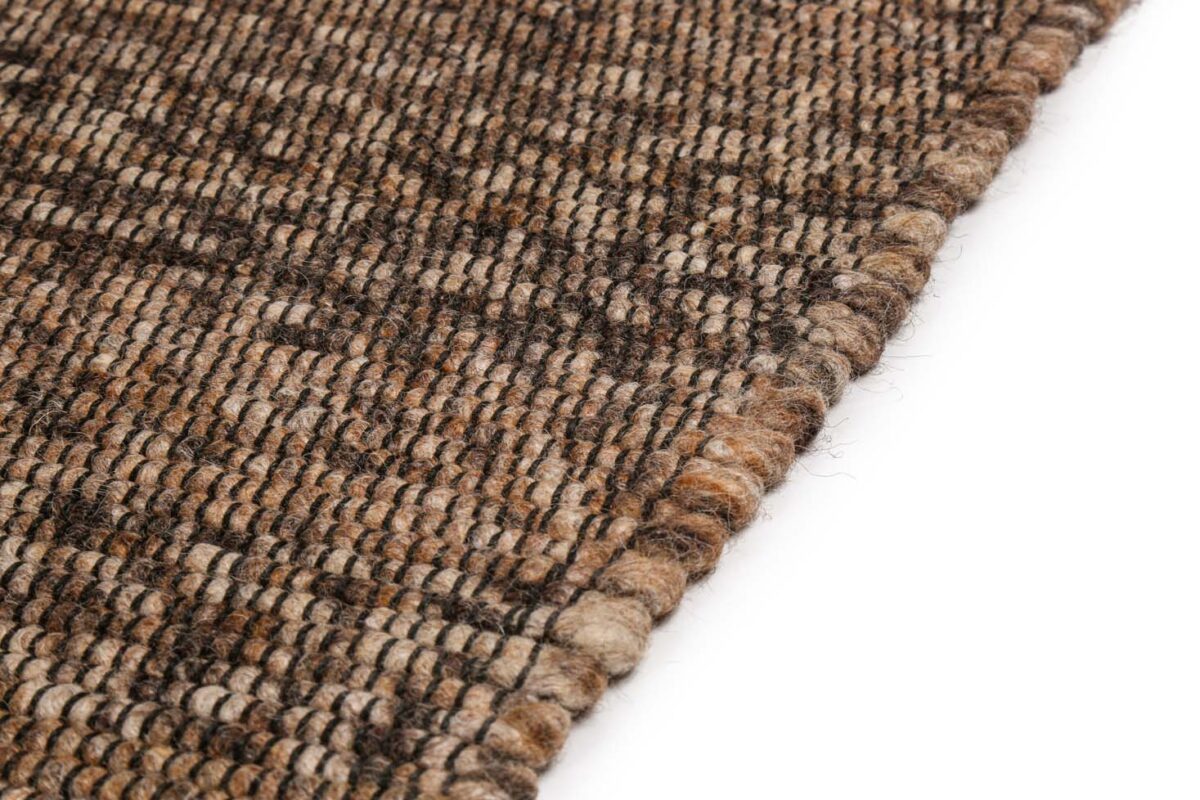 Close-up van de rand van het tapijt Bressano Brown 623 200x300, met een grof geweven structuurpatroon in bruin, beige en taan tegen een witte achtergrond.