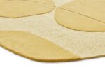 Een close-up van het Bolsena Lago Wild Wonder 250x225 tapijt toont het zachte beige en gele oppervlak met textuur, grote verhoogde geometrische vormen en afgeronde hoeken.
