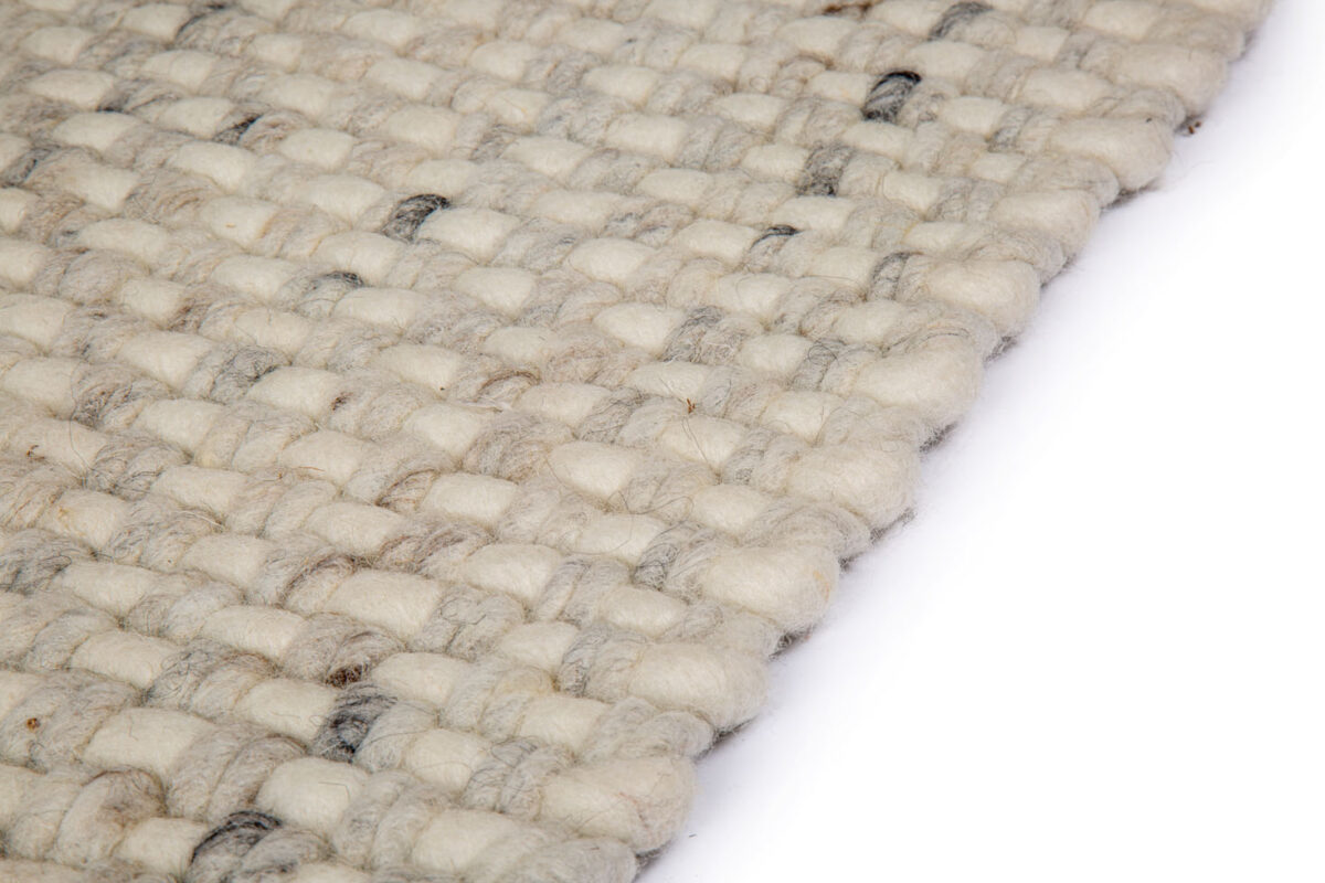 Close-up van het wollen Burano White Grey 001-367 vloerkleed (170x230 cm) met een grof, gestructureerd patroon in neutrale tinten, schuin afgebeeld op een witte achtergrond.