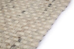 Close-up van het wollen Burano White Grey 001-367 vloerkleed (170x230 cm) met een grof, gestructureerd patroon in neutrale tinten, schuin afgebeeld op een witte achtergrond.