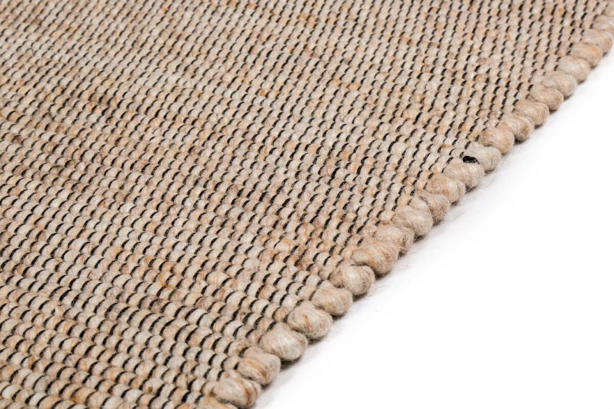 Een close-up van het tapijt Bressano Beige 142 200x300 toont het geweven beige en bruine structuurpatroon met een afgeronde rand tegen een witte achtergrond.