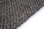 Close-up van het Burano Anthracite 614-604 vloerkleed (170x230), een donkergrijs geweven stof met textuur en dikke, afgeronde garenlussen, schuin afgebeeld op een witte achtergrond.