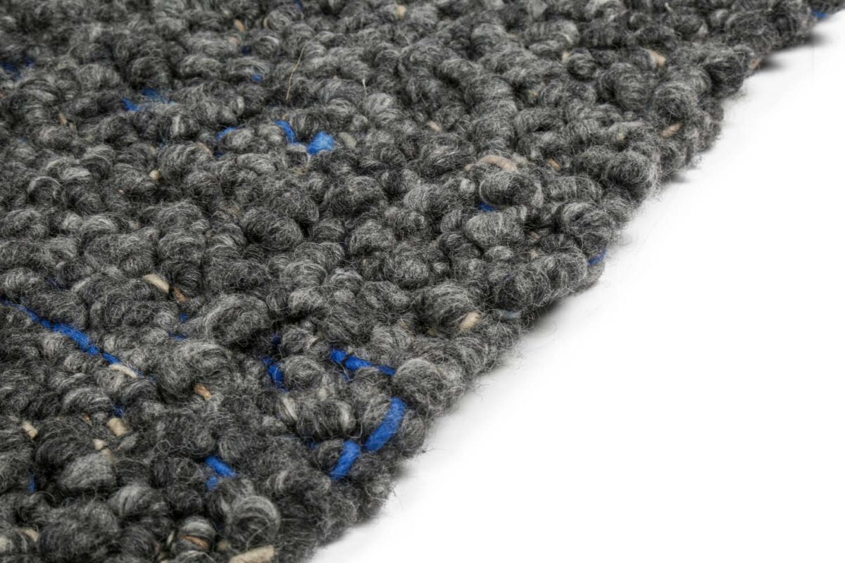 Close-up van het vloerkleed Modena Grey 916 200x300, met donkergrijs structuurweefsel met dikke lussen en vleugjes blauw en beige tegen een witte achtergrond.