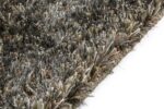 Close-up van de hoek van het New Paulo Grey mix 862 200x300 shaggy vloerkleed, met dikke veelkleurige vezels in grijs, bruin en beige op een wit oppervlak.