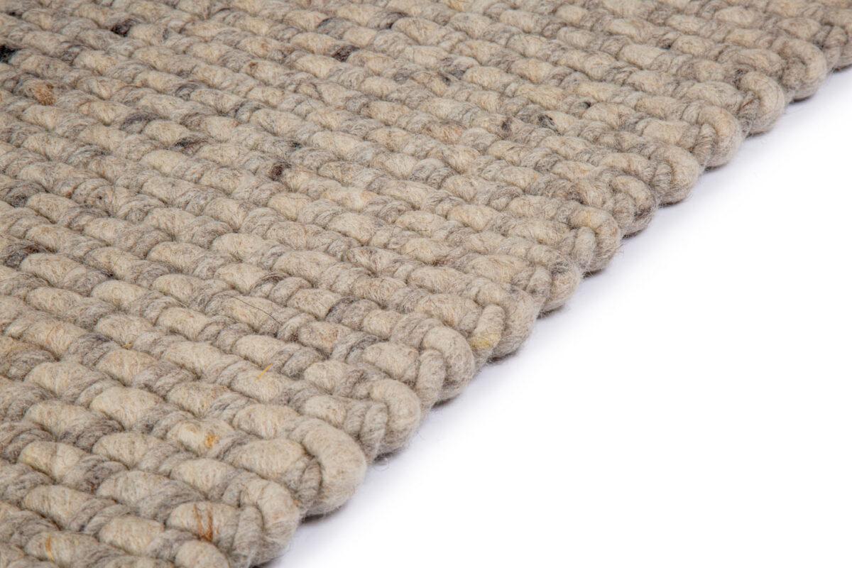 Close-up van de rand van het Burano Light Grey 616-618 200x300 tapijt, met dikke, grove lussen in een geweven textuur, tegen een witte achtergrond.