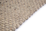 Close-up van de rand van het Burano Light Grey 616-618 200x300 tapijt, met dikke, grove lussen in een geweven textuur, tegen een witte achtergrond.