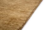 Close-up van het San Stefano Dark Beige 08 200x300 vloerkleed, met een taankleurig, gestructureerd oppervlak met een subtiel, onregelmatig patroon. Een hoek van het tapijt is te zien tegen een witte achtergrond.